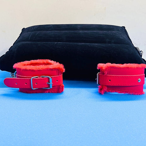 Red leather cuffs with fur trim on a blue surface