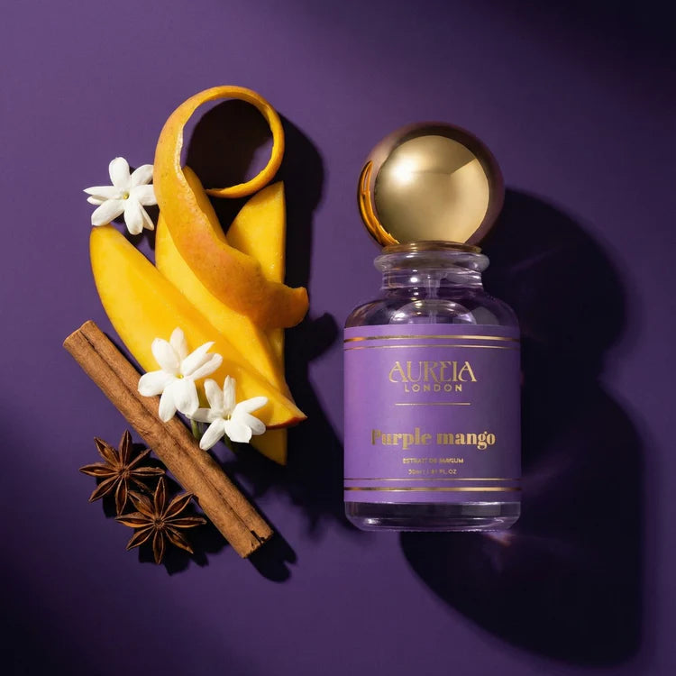 Aureia London 'Purple Mango' perfume bottle with mango slices, flowers, and cinnamon on a purple background