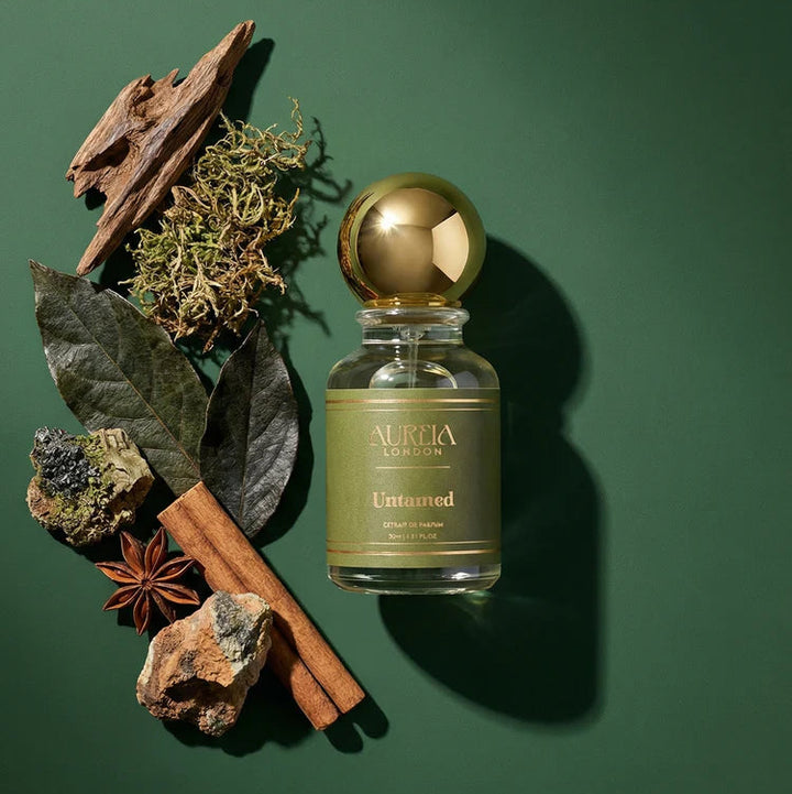 Perfume bottle labeled 'Aukia' with natural elements on a green background