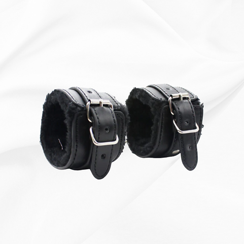 Pair of black leather cuffs with fur lining on a white background