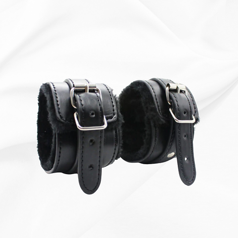 Pair of black leather cuffs with metal buckles on a white background