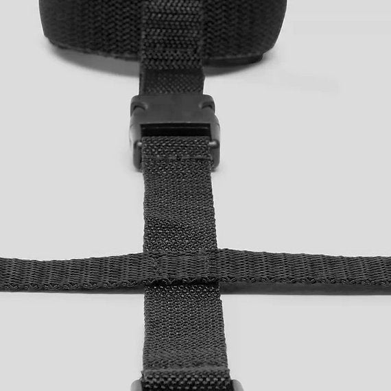 Close-up of black webbing straps with a buckle on a light gray background