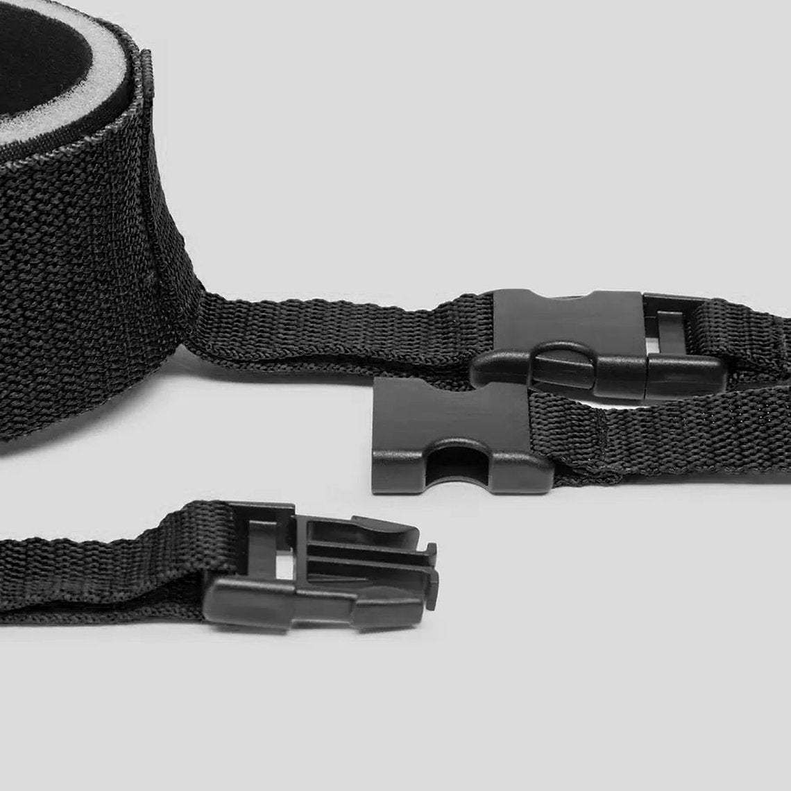 Black webbing strap with a metal buckle on a light gray background