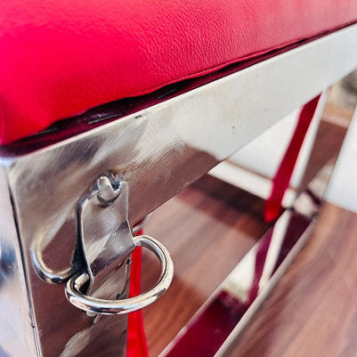 Close-up of a shiny chrome handle on a red vehicle seat.
