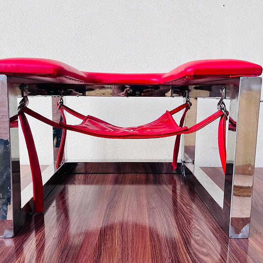 Modern red bench with chrome legs on a wooden floor.