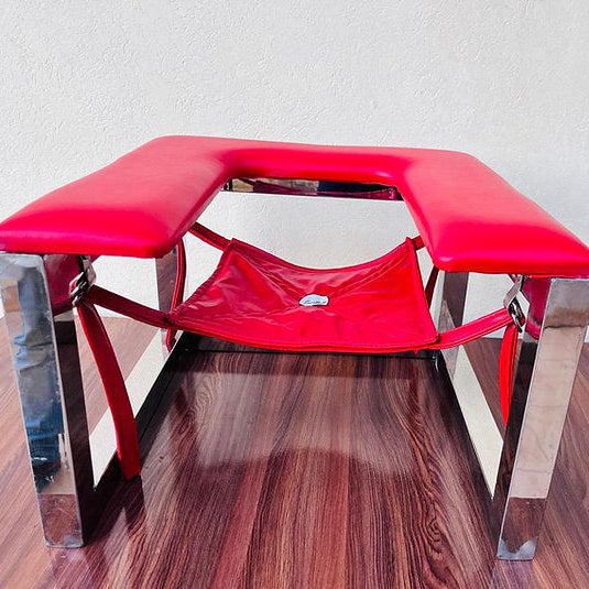 Red massage table with metal legs on a wooden floor