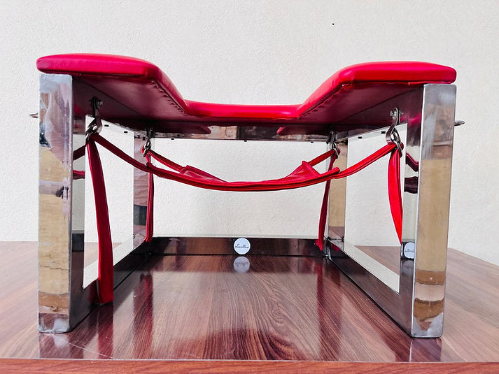 Modern red chair with transparent legs on a wooden floor.