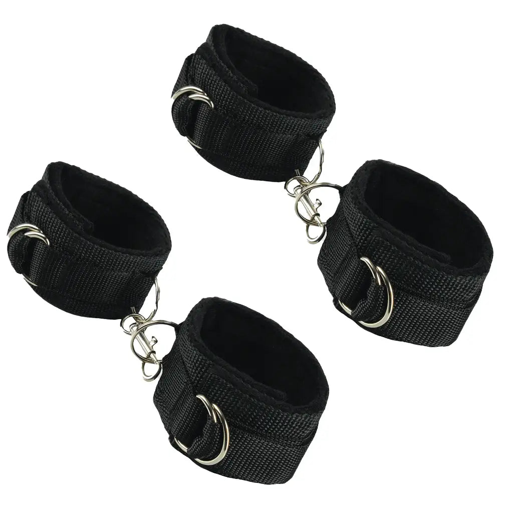 Four black wrist cuffs with metal rings on a white background