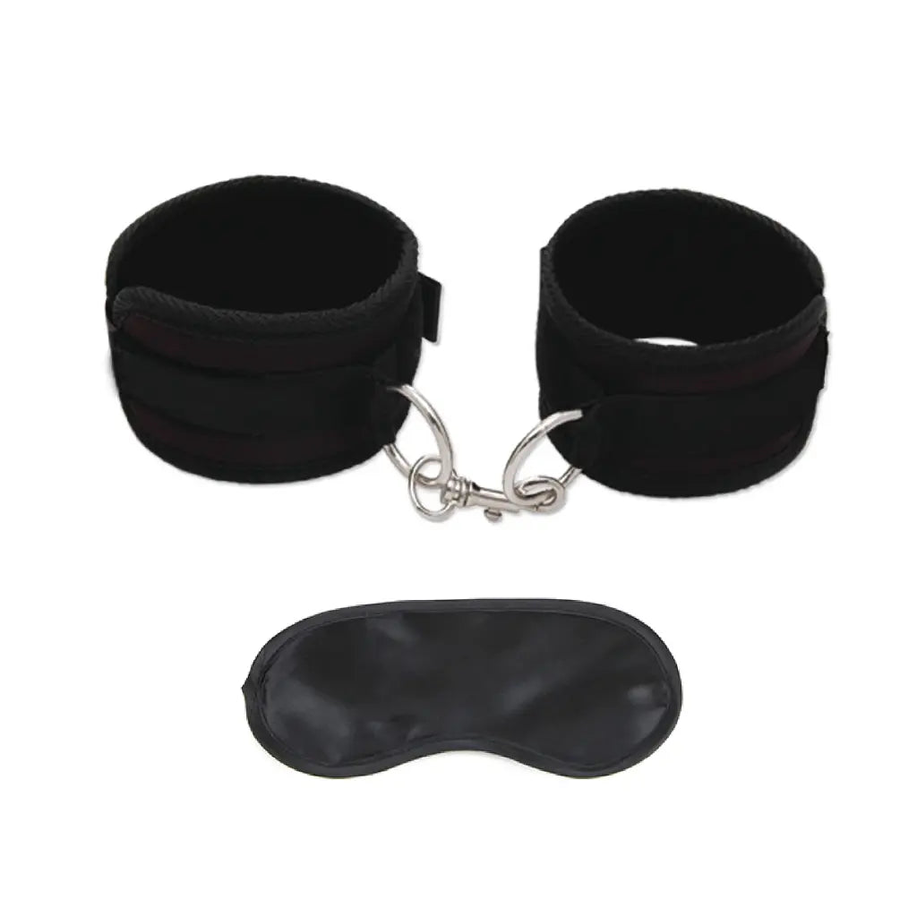 Black wrist cuffs and eye mask set on a white background